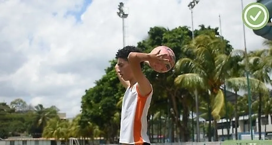 étape 1 ramasser le ballon avec les deux mains, une de chaque côté du ballon.